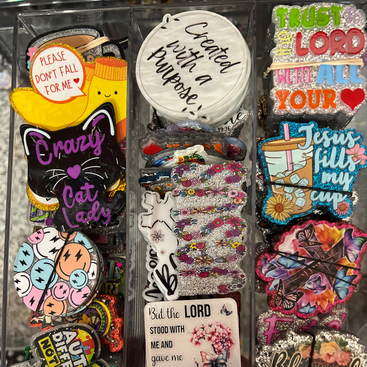Collection of colorful stickers and pins on a clear tray