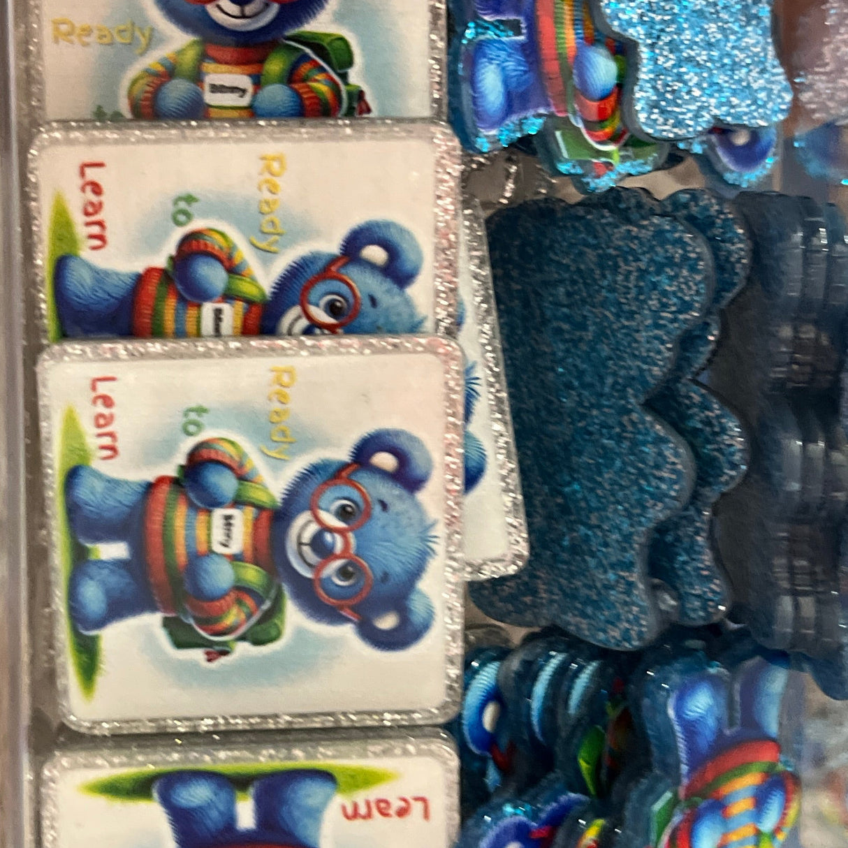 Colorful decorative items in a clear plastic case held by a hand.