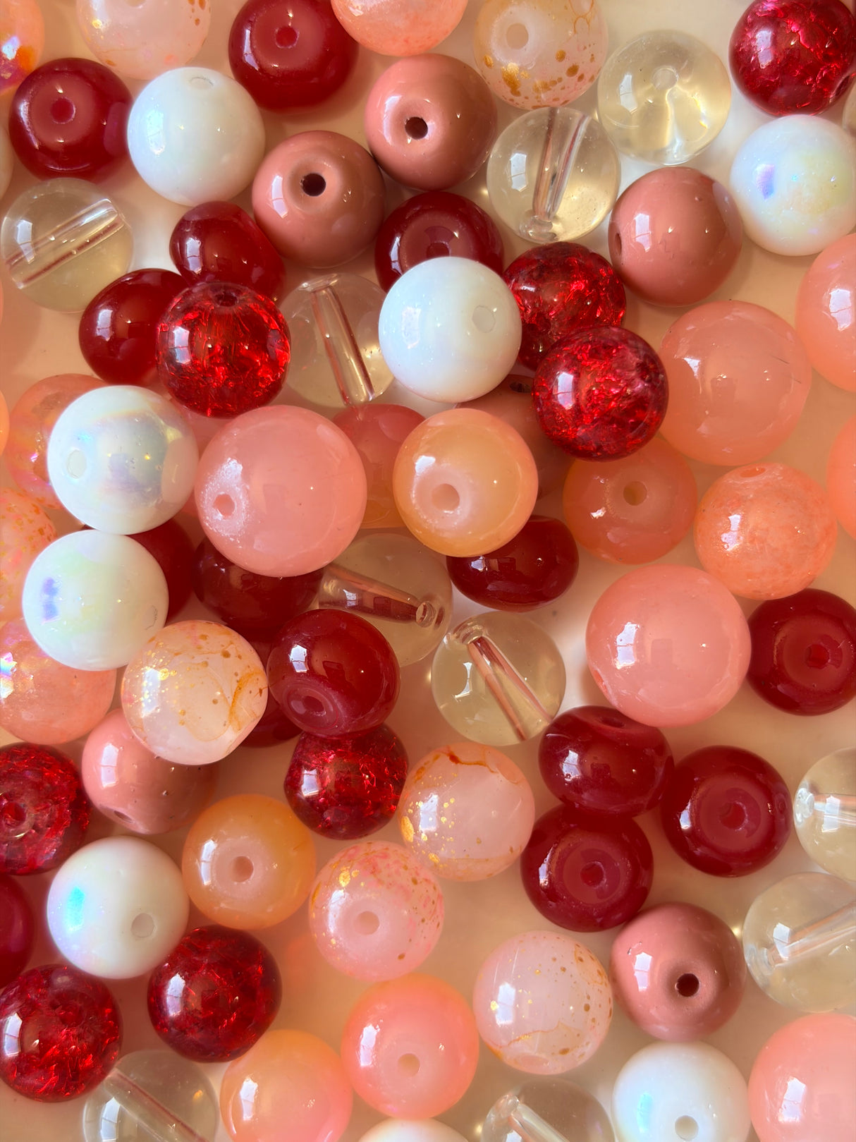 Assorted red, pink, and white beads on a light background