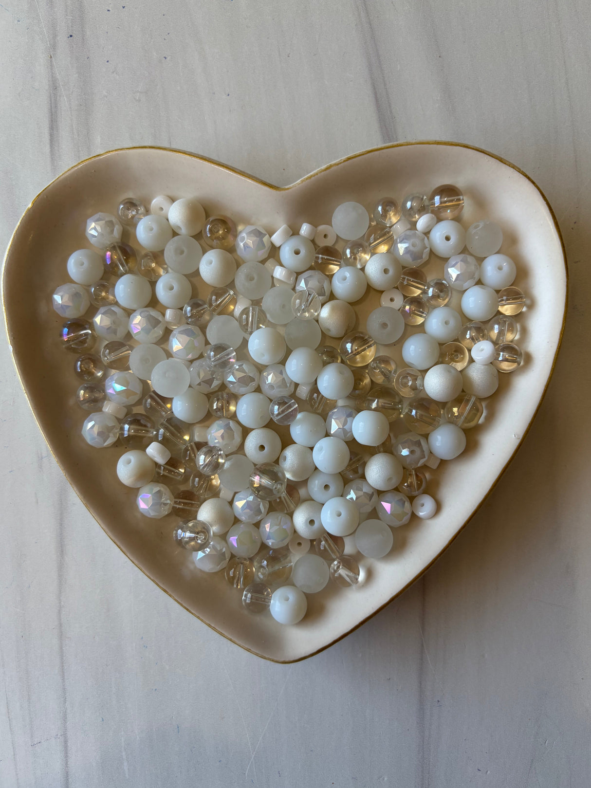 Heart-shaped dish filled with pearls on a light wooden surface