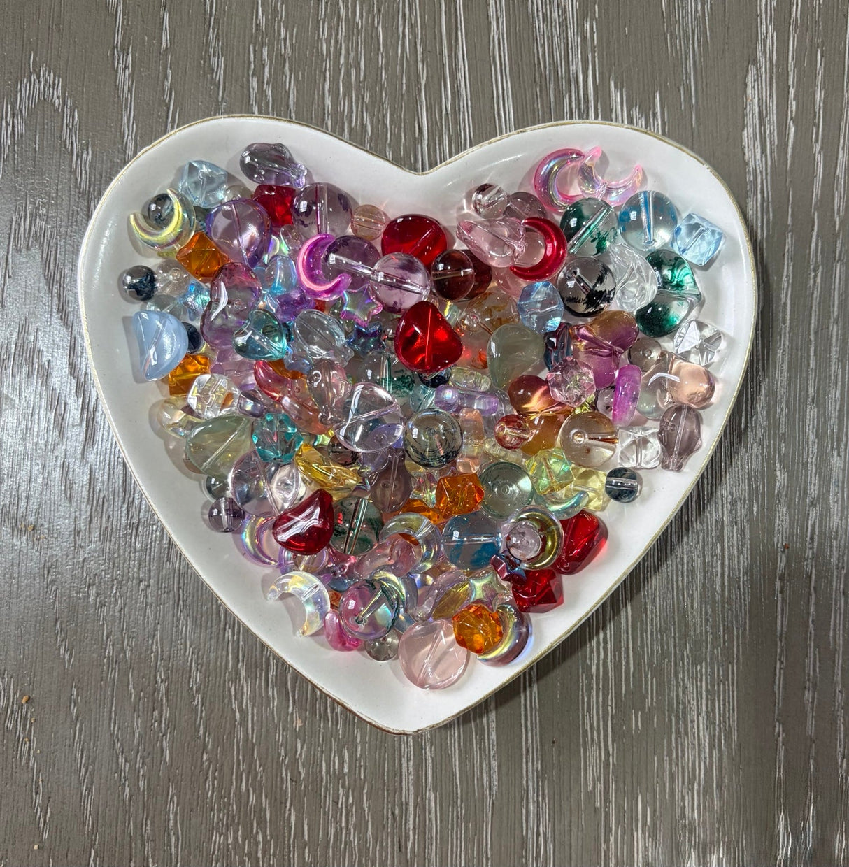 Prism Glow Glass Bead Mix translucent multicolor glass beads with hearts moons stars rounds and assorted shapes in a heart-shaped dish