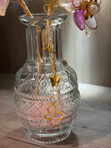 Decorative glass vase with butterfly charm on a wooden surface