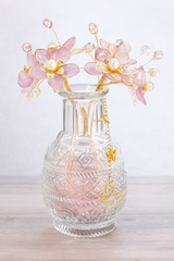 Decorative glass vase with pink butterfly lights on a wooden surface