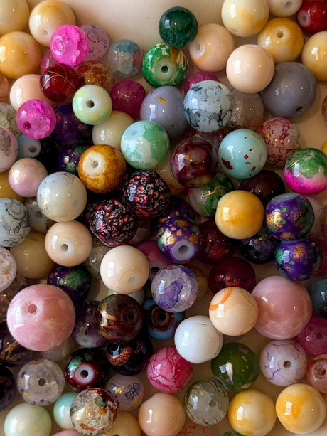 Assorted colored beads in a heart-shaped dish on a light wooden surface
