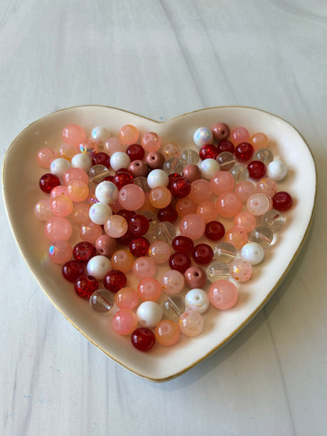 Heart-shaped dish filled with multicolored beads on a light background