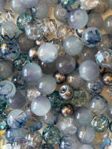 Collection of marbles in various colors and sizes on a reflective surface