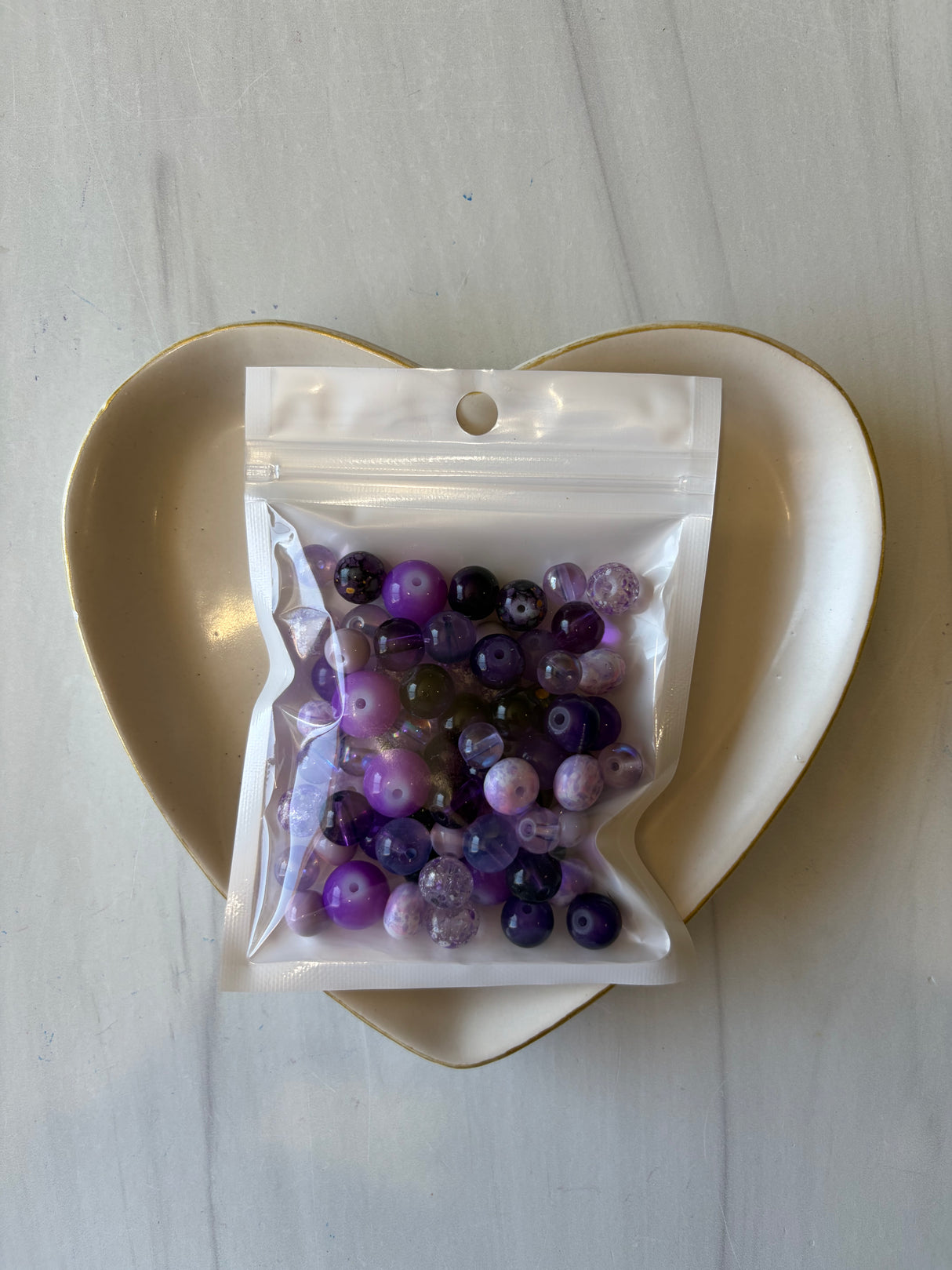 Bag of multicolored beads on a white plate with a white background