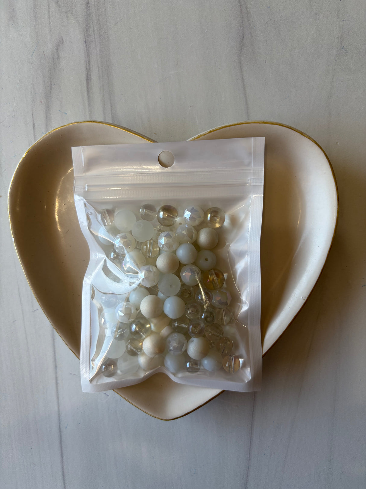 Bag of pearls on a white plate with a marble background