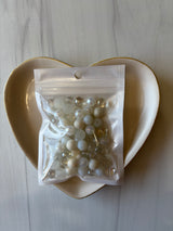 Bag of pearls on a white plate with a marble background