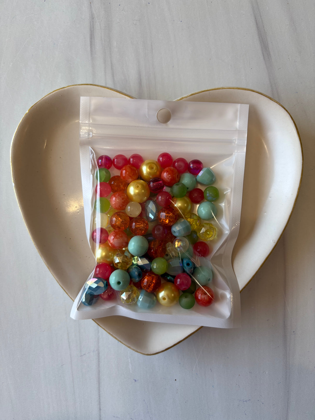 Bag of multicolored beads on a white dish with a white background