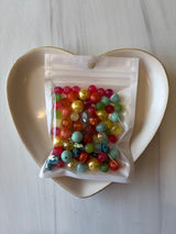Bag of multicolored beads on a white dish with a white background