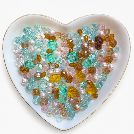 Bayou Royalty Luxe Mix glass bead assortment in a heart-shaped dish on a white background