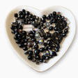 Black Diamond Luxe Mix glass bead assortment in a heart-shaped dish on a white background