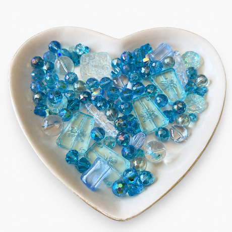 Blue Lagoon Luxe Mix glass bead assortment in a heart-shaped dish on a white background