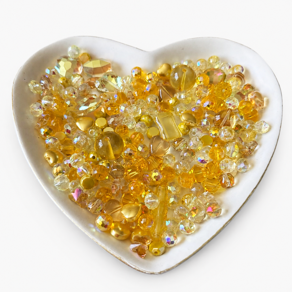 Golden Sunshine Luxe Mix glass bead assortment in a heart-shaped dish on a white background