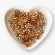 Honey Blush Luxe Mix glass bead assortment in a heart-shaped dish on a white background