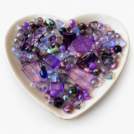 Lavender Nights Luxe Mix glass bead assortment in a heart-shaped dish on a white background