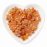 Orange Glow Bling Bling Lux Mix sparkling orange glass bead assortment in heart-shaped dish