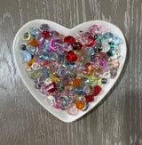 Prism Glow Glass Bead Mix translucent multicolor glass beads with hearts moons stars rounds and assorted shapes in a heart-shaped dish