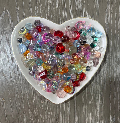 Prism Glow Glass Bead Mix translucent multicolor glass beads with hearts moons stars rounds and assorted shapes in a heart-shaped dish