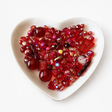 Ruby Love Luxe Mix glass bead assortment in a heart-shaped dish on a white background