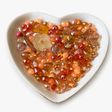 Tangerine Glow Luxe Mix glass bead assortment in a heart-shaped dish on a white background